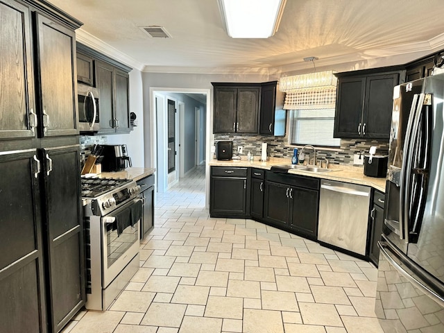 kitchen with appliances with stainless steel finishes, tasteful backsplash, sink, hanging light fixtures, and ornamental molding