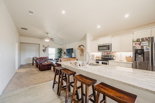 kitchen featuring a kitchen breakfast bar, open floor plan, visible vents, and appliances with stainless steel finishes