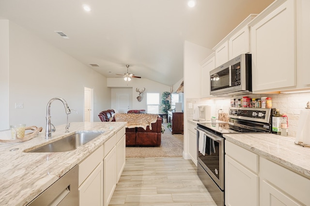 kitchen with visible vents, a sink, tasteful backsplash, stainless steel appliances, and vaulted ceiling