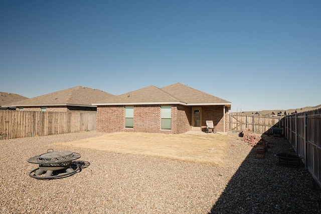 back of house with brick siding, roof with shingles, and a fenced backyard