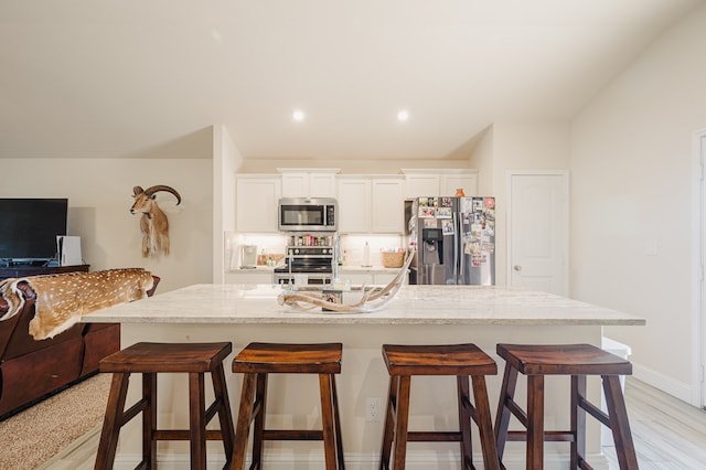 kitchen featuring white cabinetry, a kitchen breakfast bar, open floor plan, and stainless steel appliances