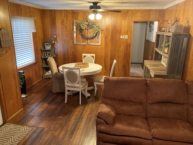dining space featuring a ceiling fan, ornamental molding, wood finished floors, and wooden walls