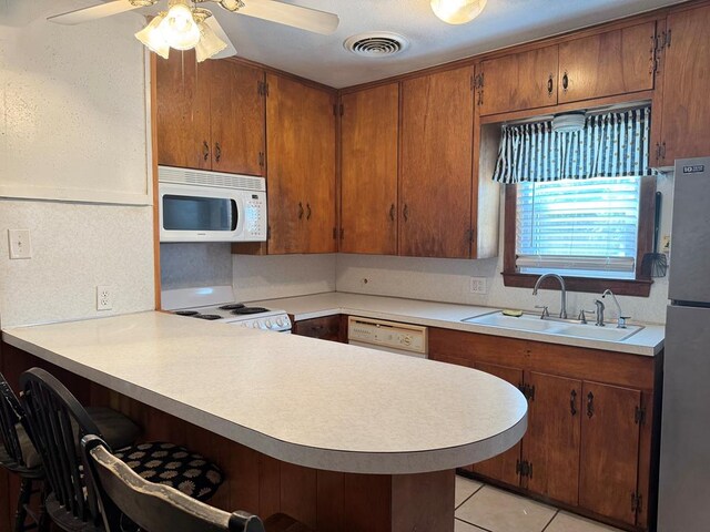 1207 W Tennessee Ave, Midland, TX 79701 - kitchen featuring white appliances, a kitchen bar, light countertops, and ceiling fan
