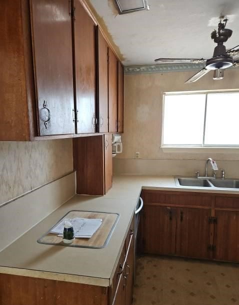 kitchen with a sink, a ceiling fan, light countertops, light floors, and brown cabinetry