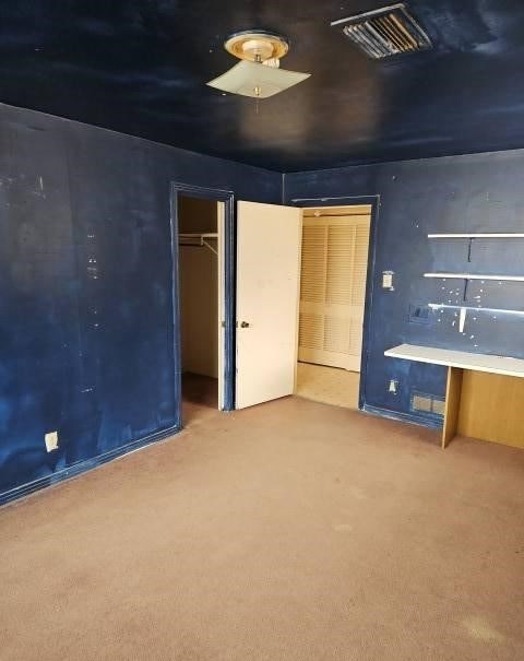 unfurnished bedroom with carpet floors, visible vents, and a closet