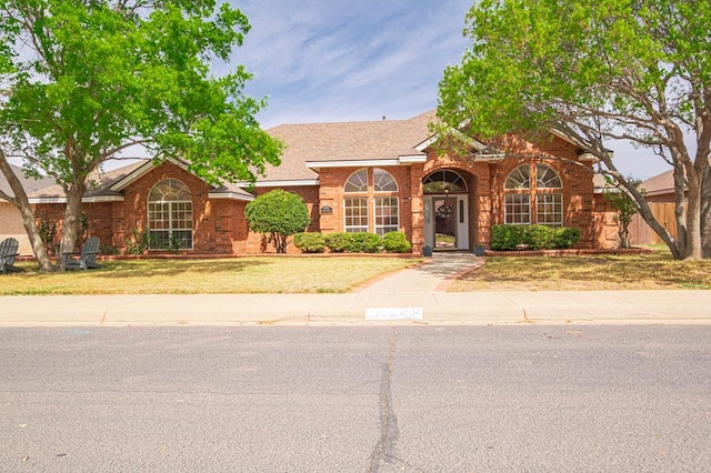 5706 Devlin Pl, Midland, TX 79707 - view of front of property with brick siding, a front yard, and roof with shingles