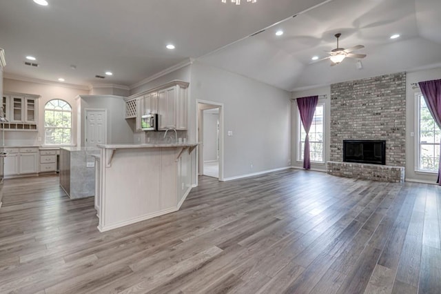 5706 Devlin Pl, Midland, TX 79707 - kitchen featuring open floor plan, stainless steel microwave, a ceiling fan, a breakfast bar, and light wood-type flooring
