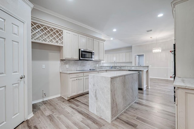 5706 Devlin Pl, Midland, TX 79707 - kitchen featuring crown molding, a kitchen island, a peninsula, appliances with stainless steel finishes, and light wood-type flooring