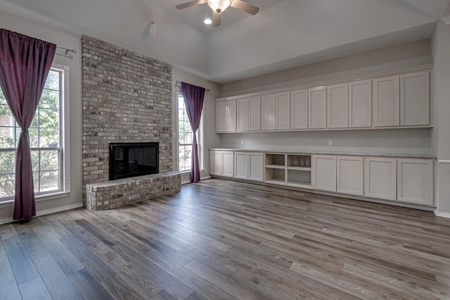 5706 Devlin Pl, Midland, TX 79707 - unfurnished living room with ceiling fan, wood finished floors, baseboards, and a brick fireplace