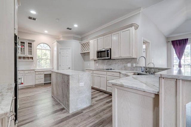 5706 Devlin Pl, Midland, TX 79707 - kitchen with a sink, a peninsula, stainless steel microwave, black electric cooktop, and light wood-type flooring
