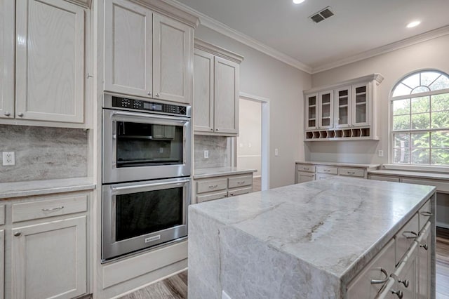 5706 Devlin Pl, Midland, TX 79707 - kitchen with double oven, wood finished floors, ornamental molding, a center island, and light stone countertops