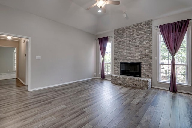 5706 Devlin Pl, Midland, TX 79707 - unfurnished living room featuring wood finished floors, a ceiling fan, a fireplace, baseboards, and lofted ceiling