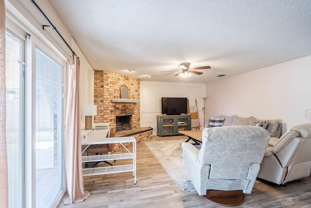 4906 San Antonio Ave, Midland, TX 79707 - living room with a textured ceiling, ceiling fan, wood finished floors, and a fireplace