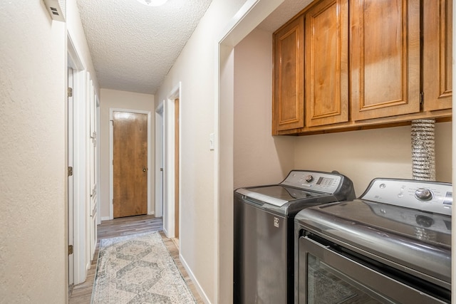 4906 San Antonio Ave, Midland, TX 79707 - washroom with cabinet space, washing machine and dryer, a textured ceiling, light wood-style flooring, and baseboards