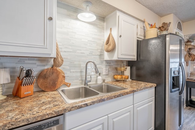 4906 San Antonio Ave, Midland, TX 79707 - kitchen featuring stainless steel appliances, a sink, white cabinetry, decorative backsplash, and a textured ceiling
