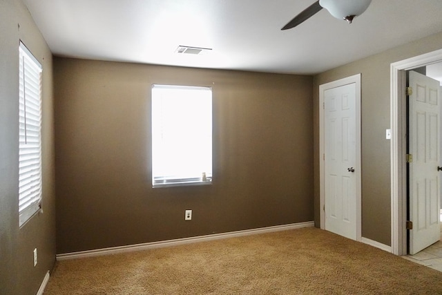 spare room with light colored carpet, ceiling fan, and baseboards