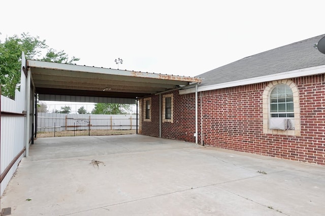 view of parking featuring fence, concrete driveway, and an attached carport
