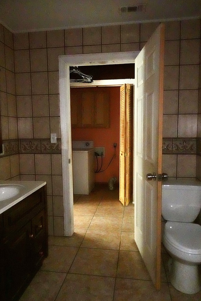 bathroom featuring tile walls, tile patterned floors, toilet, and vanity