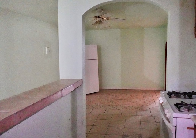 hall featuring arched walkways and tile patterned floors