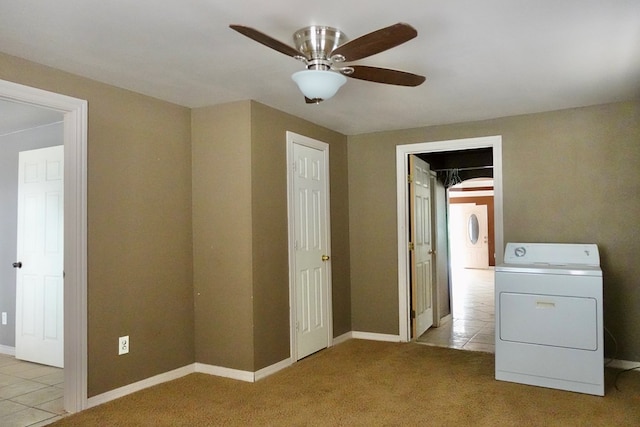 carpeted spare room featuring washer / dryer, ceiling fan, tile patterned flooring, and baseboards