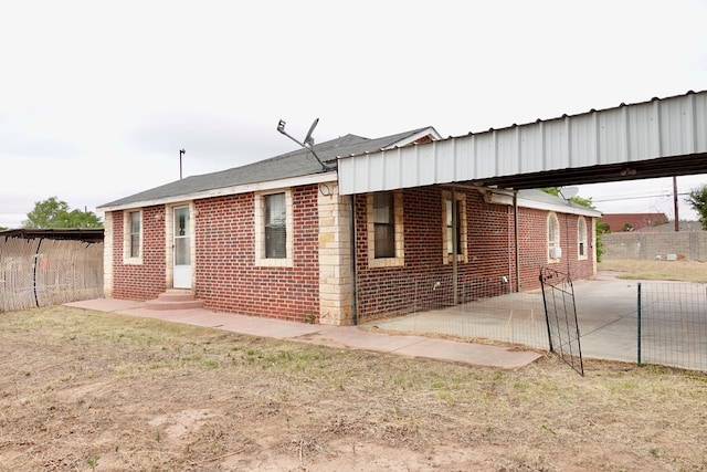 back of property featuring entry steps, fence, an attached carport, brick siding, and a patio area