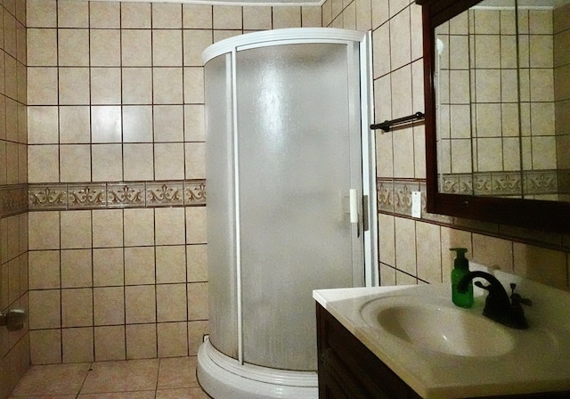 bathroom featuring tile walls, a stall shower, vanity, tile patterned flooring, and toilet