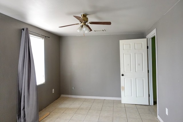 spare room featuring ceiling fan, light tile patterned floors, and baseboards