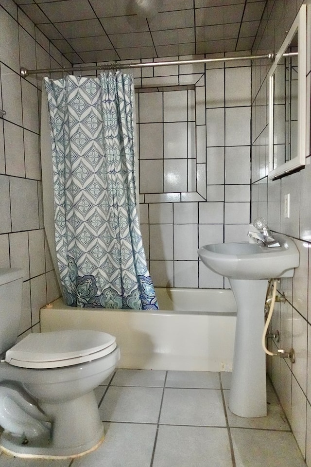 full bathroom with tile walls, tile patterned floors, toilet, and shower / tub combo with curtain