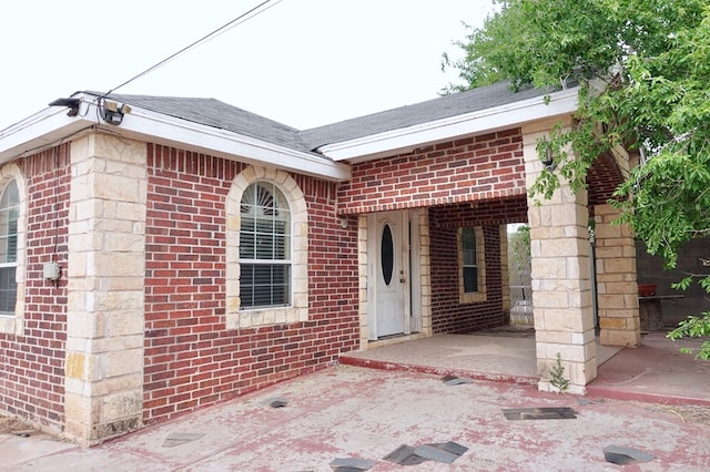 property entrance with brick siding and roof with shingles
