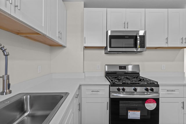 201 E Pine Ave, Midland, TX 79705 - kitchen with a sink, light countertops, white cabinets, and stainless steel appliances