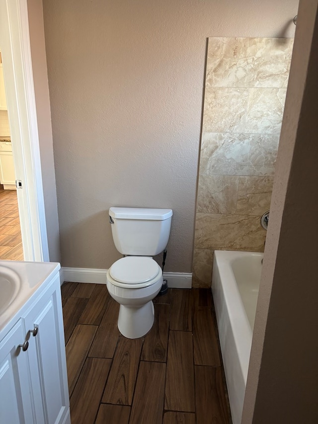 bathroom featuring toilet, vanity, and a washtub