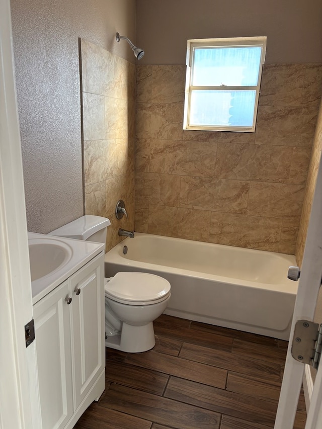 full bathroom featuring vanity, tiled shower / bath combo, and toilet