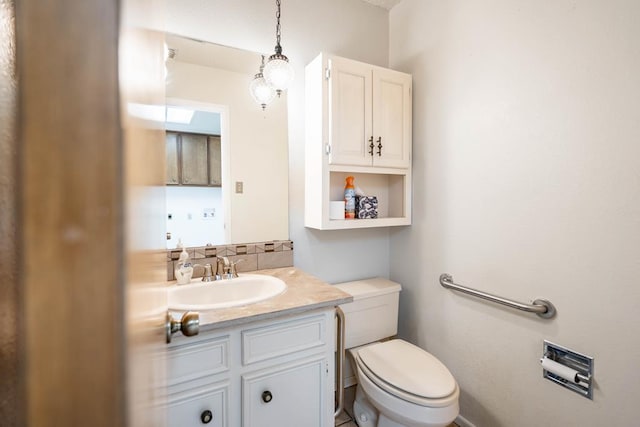 bathroom featuring vanity, toilet, and backsplash