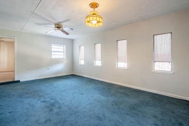 spare room featuring plenty of natural light, dark carpet, and ceiling fan