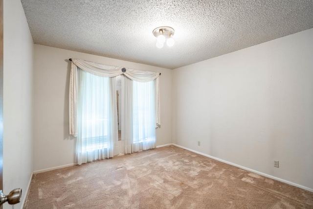 unfurnished room featuring a textured ceiling and light carpet