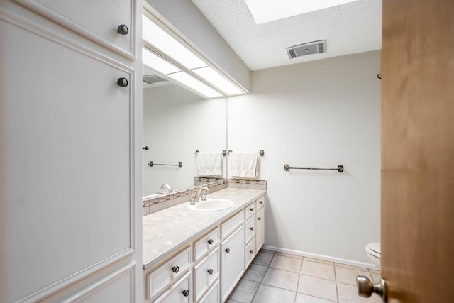 bathroom with tile patterned floors, vanity, a textured ceiling, and toilet