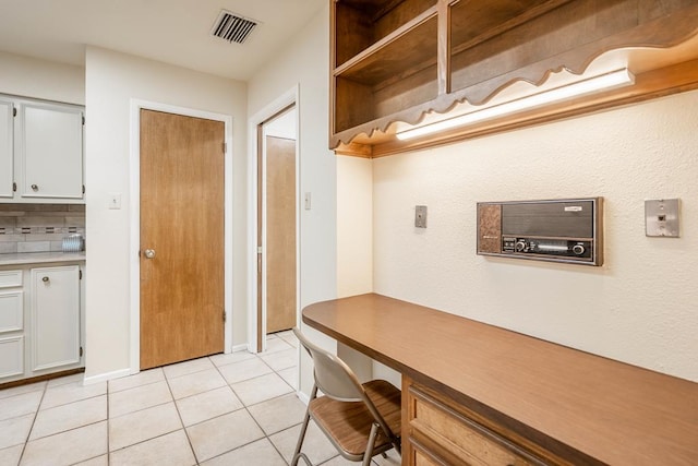 kitchen with backsplash, white cabinets, and light tile patterned flooring