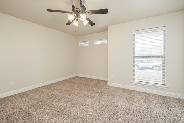 carpeted empty room featuring baseboards and a ceiling fan