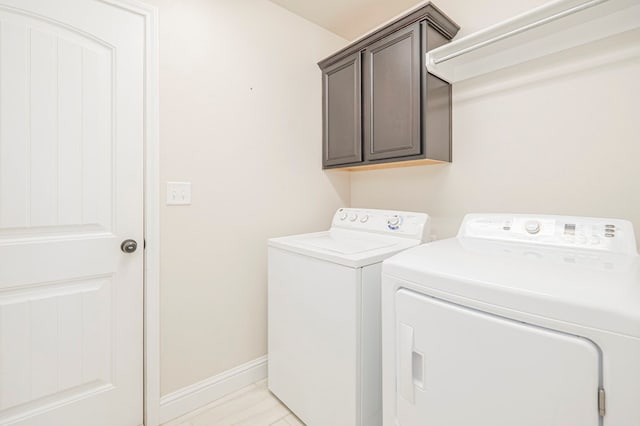 laundry room featuring washer and dryer, cabinet space, and baseboards