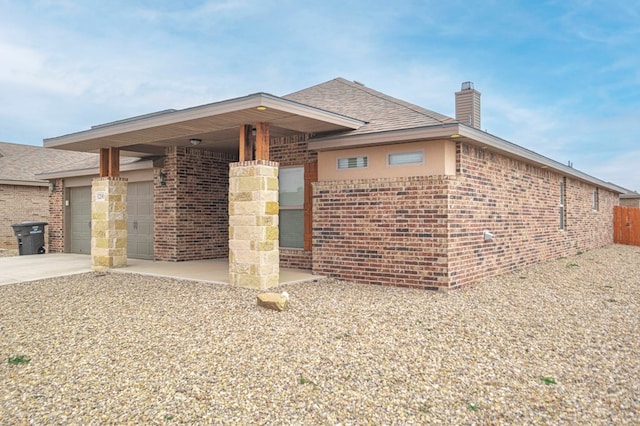 view of front of house featuring brick siding, a chimney, a shingled roof, concrete driveway, and an attached garage