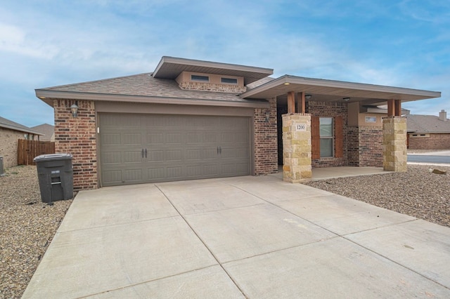 prairie-style home featuring an attached garage, roof with shingles, concrete driveway, and brick siding