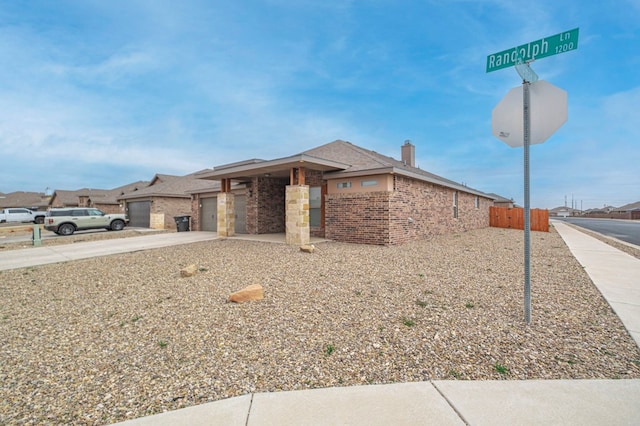 view of front of home with driveway, an attached garage, fence, and brick siding