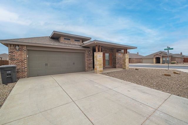 prairie-style house featuring an attached garage, concrete driveway, and brick siding