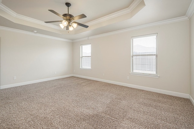 spare room with carpet floors, a tray ceiling, ornamental molding, a ceiling fan, and baseboards