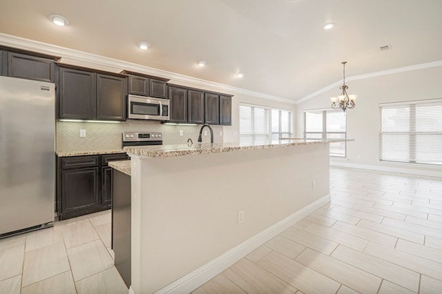 kitchen with stainless steel appliances, vaulted ceiling, hanging light fixtures, and an island with sink