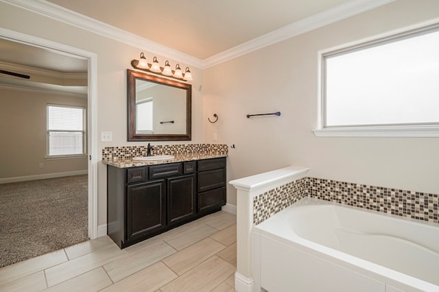 bathroom featuring a garden tub, crown molding, vanity, and baseboards