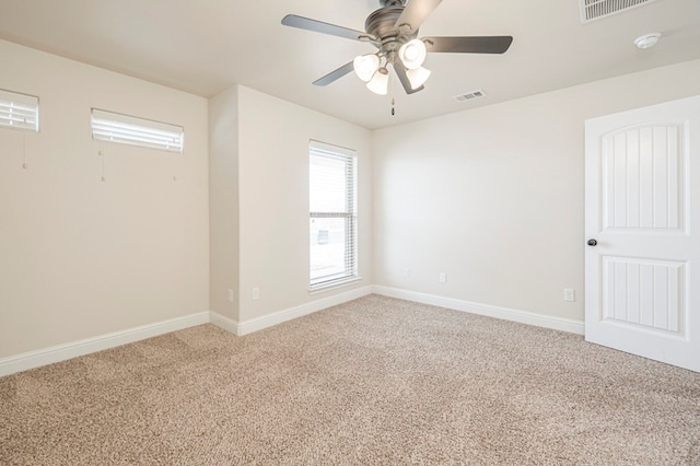 carpeted spare room with visible vents, ceiling fan, and baseboards