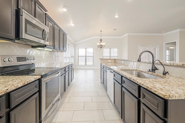 kitchen featuring light stone counters, decorative light fixtures, stainless steel appliances, vaulted ceiling, and a sink