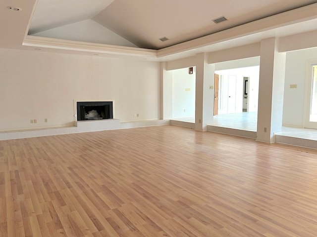 unfurnished living room with light wood-type flooring, vaulted ceiling, and a tray ceiling