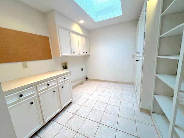 laundry area featuring cabinets, electric dryer hookup, light tile patterned floors, a skylight, and washer hookup